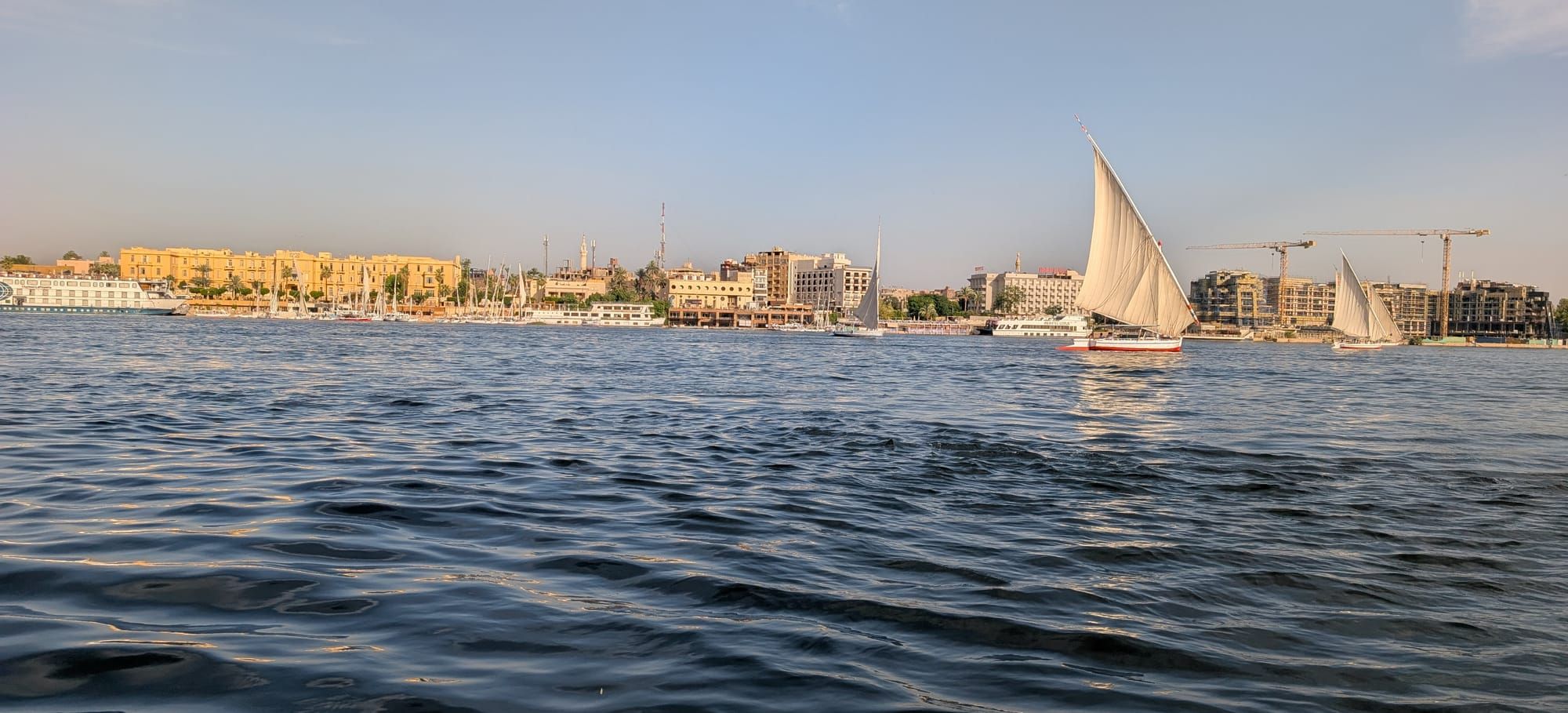 Feluccas sailing on the Nile with Luxor’s East Bank in the background.